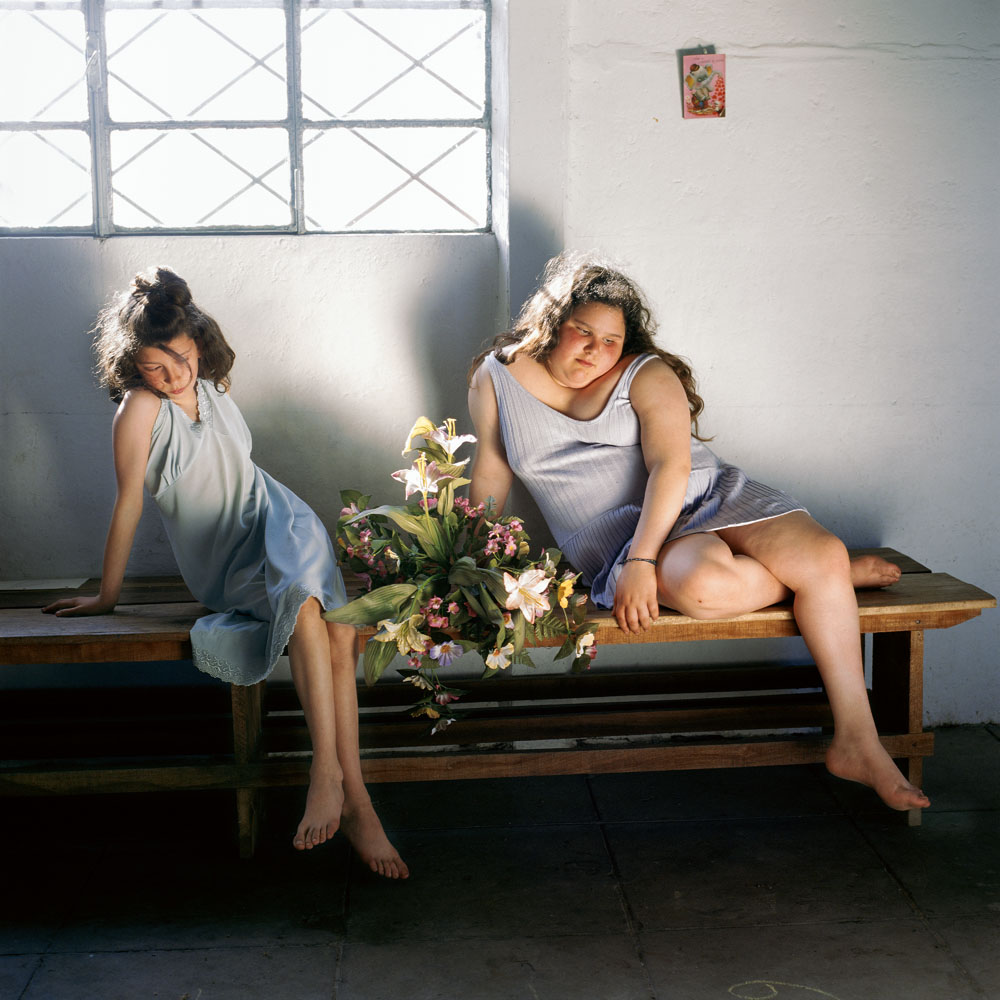 صورة لفتاتين تجلسان على مقعد تحت النافذة بواسطة أليساندرا سانغينيتي