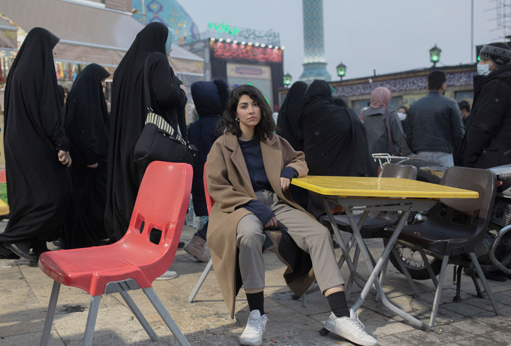 امرأة شابة تجلس أمام مسجد في طهران، إيران، تصوير أحمد حلبيزاز.