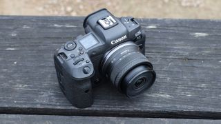 عدسة RF-S مقاس 10-18 مم f/4.5-6.3 IS STM من Canon مثبتة على كاميرا Canon EOS R5 موضوعة على مقعد خشبي مضلع