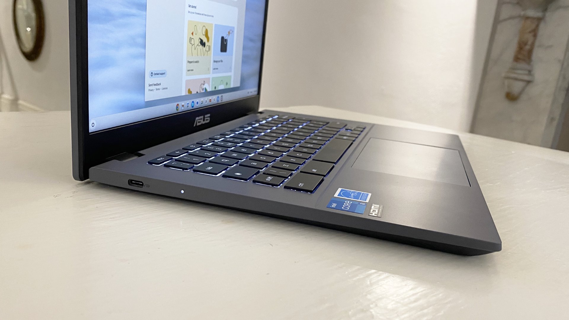 الكمبيوتر المحمول Asus Chromebook Plus مفتوح والشاشة قيد التشغيل ويجلس على المكتب