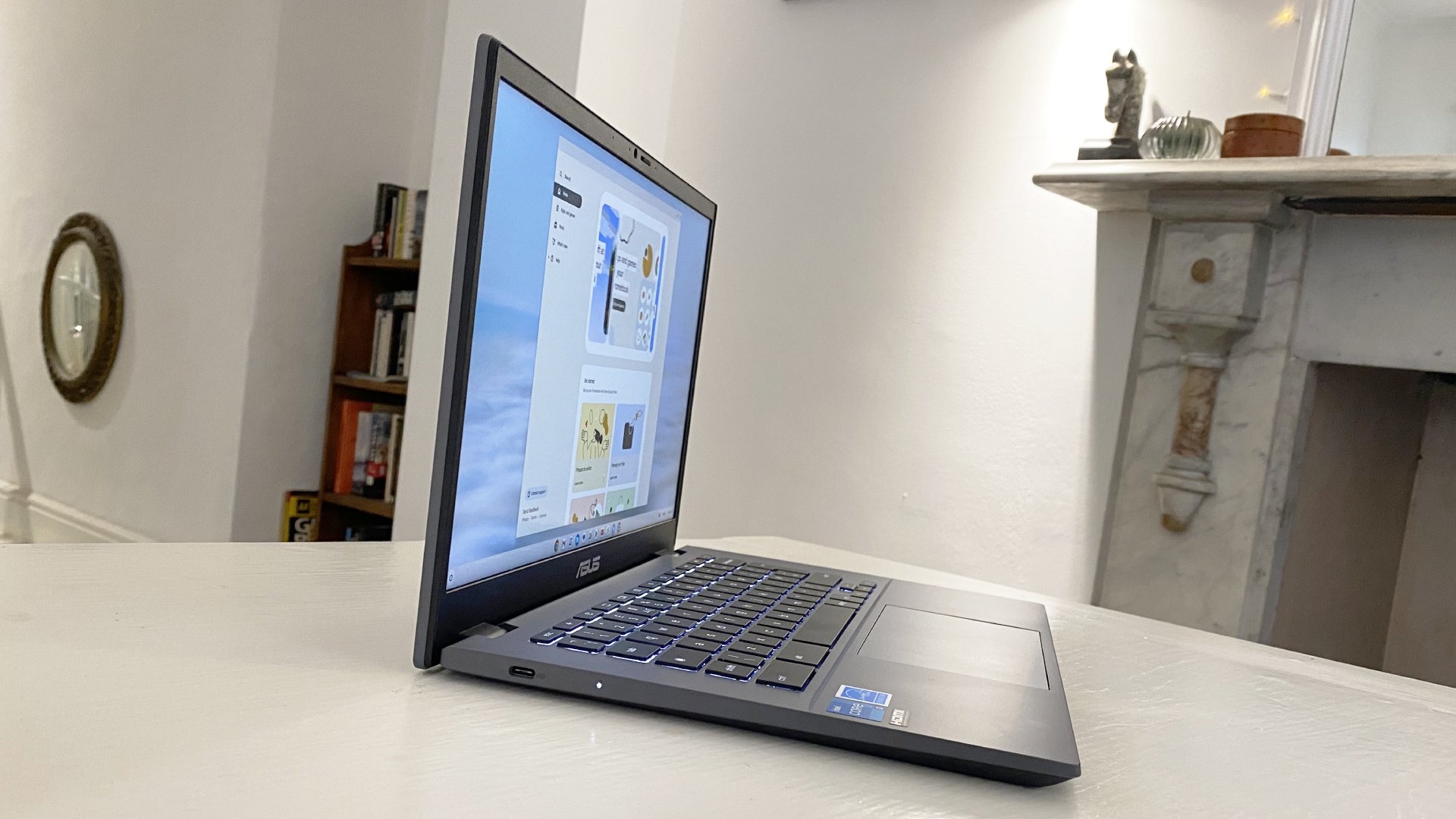 الكمبيوتر المحمول Asus Chromebook Plus مفتوح والشاشة قيد التشغيل ويجلس على المكتب